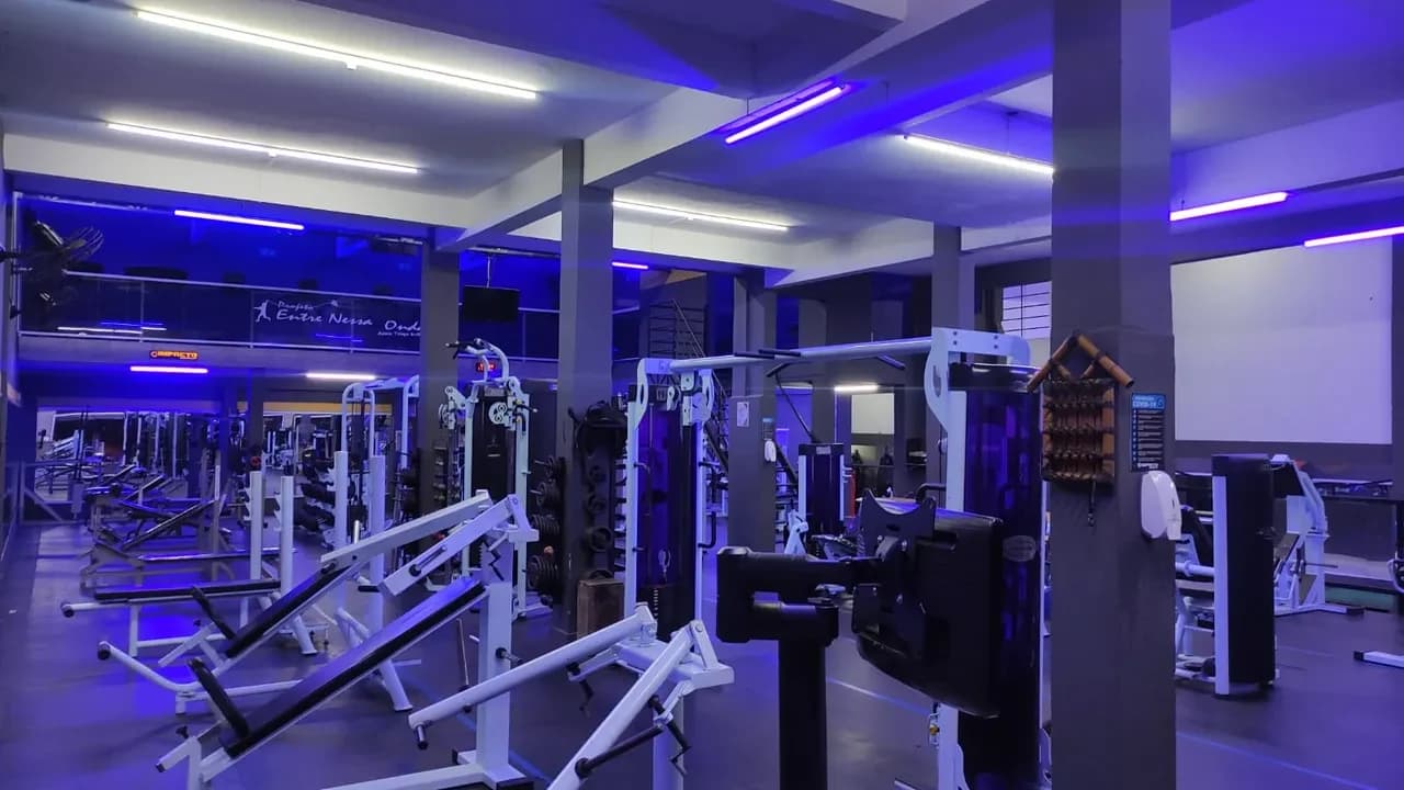 Vista panorâmica da área de musculação da Ativa Fit com iluminação azul e violeta